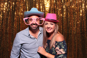 A couple in a FOTO Machines photobooth with gold sequin backdrop
