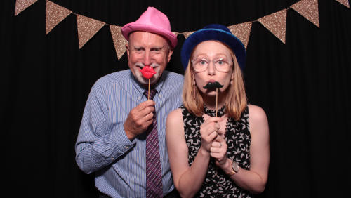 A couple in a FOTO Machines Photobooth with a black backdrop