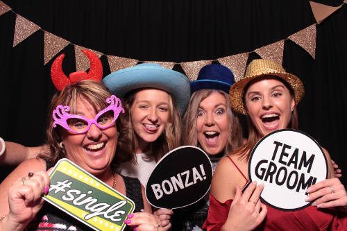 Four ladies in a photobooth with colourful props and a black backdrop