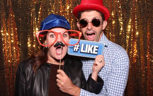 Two people having fun in a photobooth in Adelaide with a gold sequin backdrop
